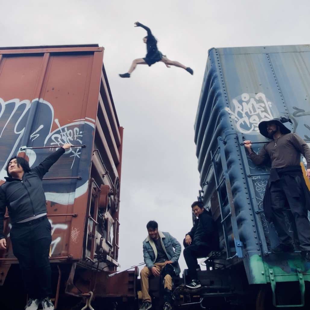 Photo of the Sigfreed members on a train while Evan jumps between the train cars